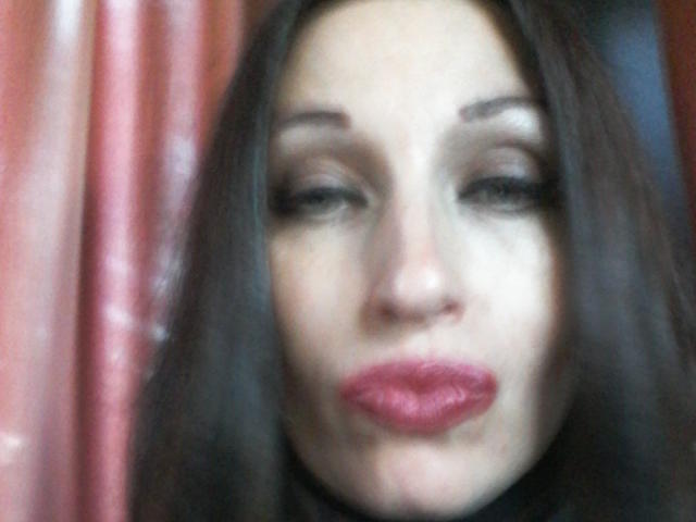 JillianPattie's face with blurred dark brown hair, smoky eyes, and bright red lipstick, making a pouty expression. Boobless, no visible ass or pussy, just a focused face.
