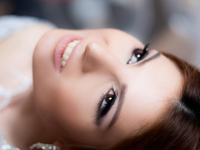 Sexydollhotx's face, brown eyes, smiling with white teeth, smooth pale skin, brown hair, subtle makeup, close-up shot, slightly tilted, looking up, soft light, gentle expression.