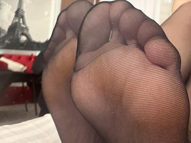 NancyChaude's feet in black sheer stockings, showing her toes and soles. Her feet are up, taking up most of the frame. Her toes are slightly curled.