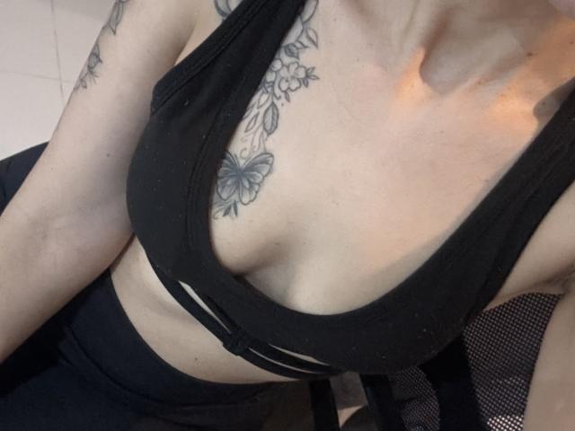 LaurentColin's tits are visible in a black sports bra, showing a floral tattoo above the cleavage. She's got a slinky, light-skinned upper body.