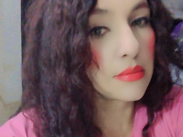 Close-up of LuluFrancaise with curly brown hair, pale skin, and bright red lipstick. She's wearing a pink top, with a smudged red mark on her right cheek. Fucking sexy.