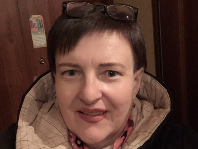 MargieEvans has short brown hair, blue eyes, and is wearing glasses on her head. She's smiling with a pink shirt and a checkered jacket. Her tits are small.