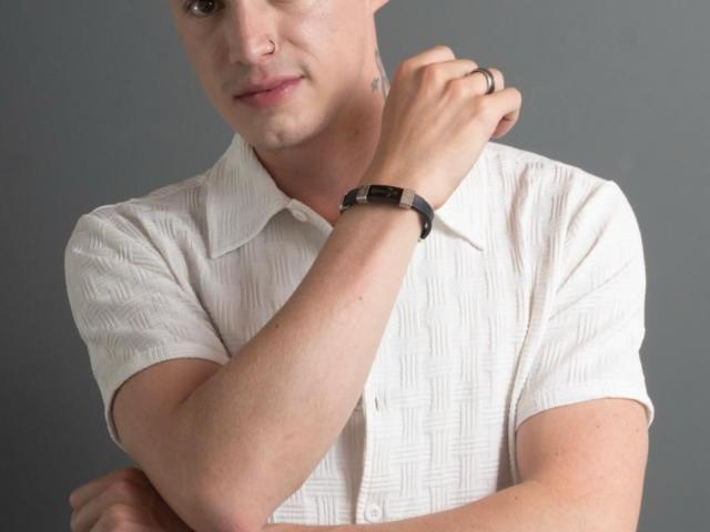 ErosHot has a light skin tone, short hair, and is wearing a white, textured, short-sleeve shirt with a black wristwatch, crossing arms, and looking at the camera.
