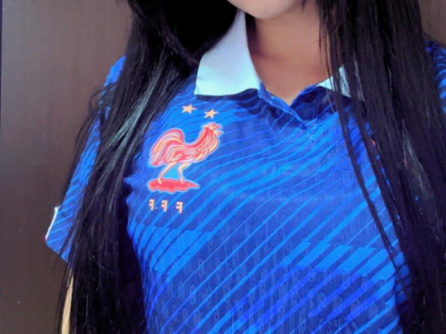 Kkatalina's blue soccer jersey with red rooster and yellow stars, her long black hair covering her face, and her medium-sized tits visible under the fabric.