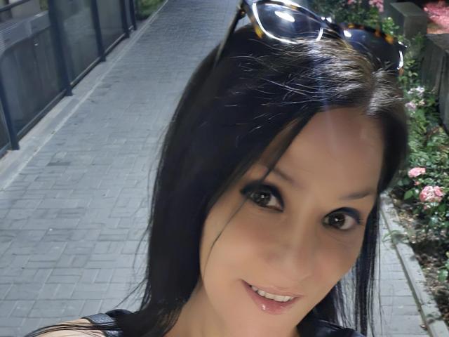 JoliDanielle has black hair, brown eyes, and a slight smile. She's wearing sunglasses on her head, with her lips slightly parted. Her ass is not visible.