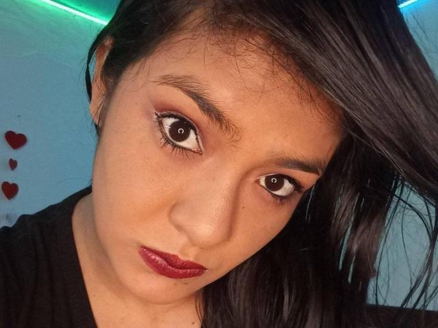 ArianithaXox's face, brown eyes, red lipstick, dark straight hair, black shirt, looking at camera, slight tilt, cute, sexy, medium skin tone, subtle eyebrow, small nose, soft expression.