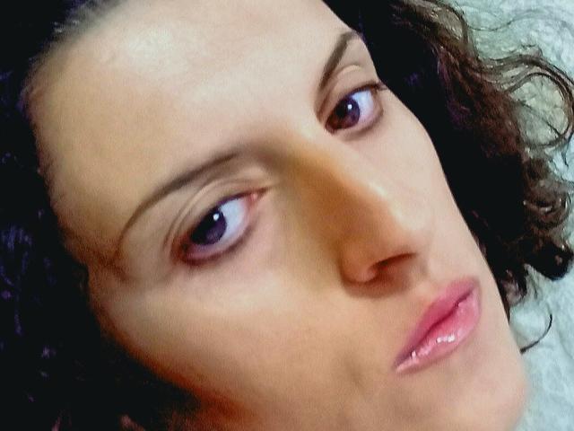 AudreyDaisy's face, showing her brown curly hair, purple eyes, and pink lips, with a slightly bored or tired expression. Her skin is light and smooth.