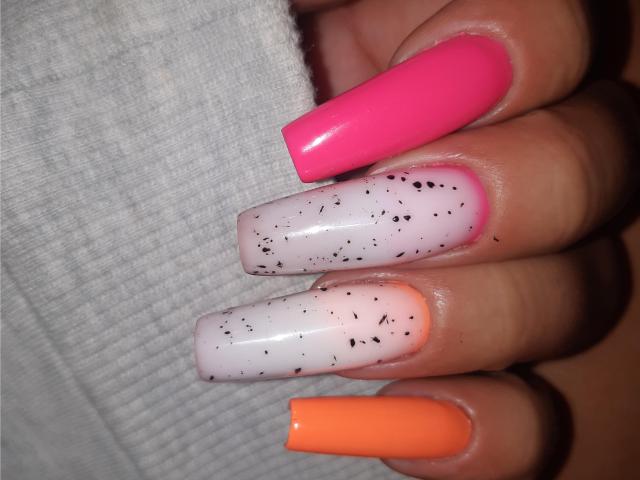 ExquisDunya's nails are painted with bright pink, white with black specks, and orange polish. Her long, shiny nails are super cute and sexy.