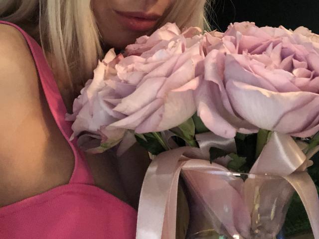 AlisaAleksandr's pink tank top with a cutout, her blonde hair, and her pink rose bouquet with silky ribbons, all in a tight shot. Her tits partially visible.