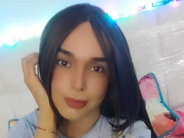 Jhovanna ha i capelli neri e lisci, gli occhi marroni e il rossetto rosso. Indossa una camicia azzurra, ha un braccialetto alla mano destra ed è rivolta verso la fotocamera..