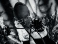 Black-and-white photo of AmySpider with a mask, glasses, and black gloves holding a rope, wearing a latex outfit with cat ears and a ringed nose.