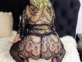 VAlica with curly blonde hair, wearing a black lace dress, kneeling on a white fluffy surface, black thigh-high stockings, showing her lace-covered ass and back.