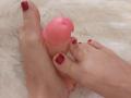 MousseAuChocolat's toes with red nail polish holding a pink dildo, showing a tight grip around the head. White fluffy background.