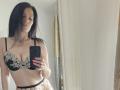 JoliDanielle with wet black hair, wearing black and white lace bra and matching panties, taking a mirror selfie with a black phone. Her right hand holds the phone, nails painted red.