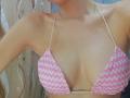 DianaShane's small pink and white crochet bikini top shows her bare, tan-lined tits with thin beige straps. Her collarbone is visible, and her arms are slightly raised.