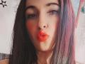 LuluFrancaise with pouty, bright red lips, dark straight hair, and a nose piercing, looking directly at the camera, showing off her full lips and slightly flushed cheeks.