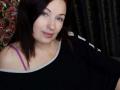 MarleneDavies has pale skin, dark brown hair, blue eyes, and small tits. She's wearing a black shirt with a purple bra strap showing, smiling softly.