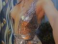 DianaShane's shiny, snake-patterned dress with a deep V-neck, showing her large, exposed tits and a gold necklace with a small heart charm. Peacock feathers in the background.