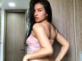 EmilyJensenn with long black hair, pink lace bralette, looking back, showing her tits, slim, tan skin, slightly parted lips, wooden door in the background, hands on her ass.