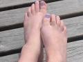 MollyMarmalade's feet with purple-painted toenails, toes slightly curled, resting on wooden planks. Her skin is pale, and the nails are neatly trimmed.