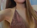 DianaShane with long brown hair, wearing a sparkly brown halter top, exposing her armpits and showing her bare cleavage. Her face is partially visible.